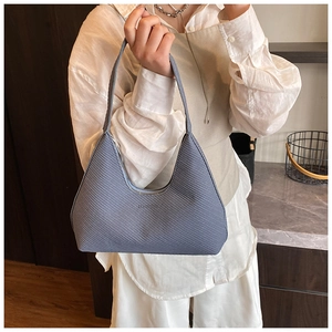 Haze blue textured hobo bag with zip closure and curved silhouette on wooden background