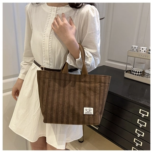 Close-up of brown corduroy tote bag featuring a Camping patch and vertical stripe texture