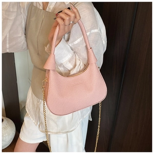 Detail of pink houndstooth underarm bag with gold chain strap and crescent shape