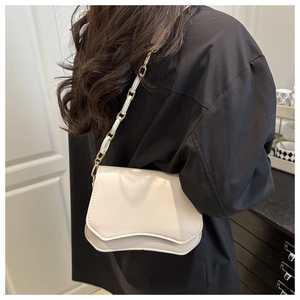 Detail of a creamy white crossbody bag featuring irregular wavy flap and resin chain strap