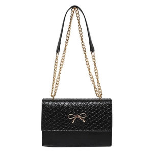 Sac bandoulière urbain noir avec rabat tissé et décoration de nœud en métal doré chic