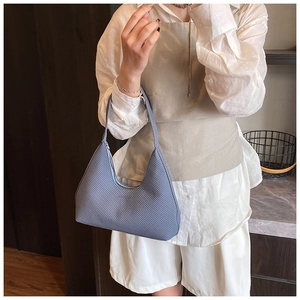 Detail of light blue hobo bag with fabric texture and slender handle in lifestyle setting