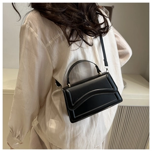 Détails du sac à main minimaliste en cuir noir avec rabat ondulé et finitions dorées
