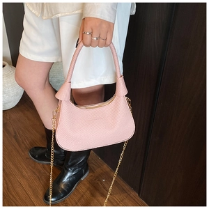 Detail of pink crescent bag showing woven texture, knotted handle and gold chain