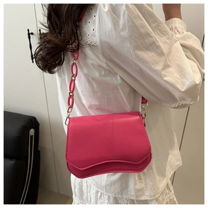 Detail of rose pink leather crossbody bag with chunky chain strap and gold hardware