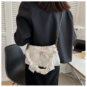 Detailed view of white ribbon shoulder bag with gold chain and bow decoration