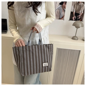 Close-up of corduroy tote bag with striped texture and camping label in lifestyle setting