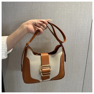Detail of vintage patchwork handbag with brown leather, beige canvas, and gold metal buckle