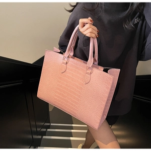 Detail of pink crocodile embossed tote bag texture with minimalist double handles