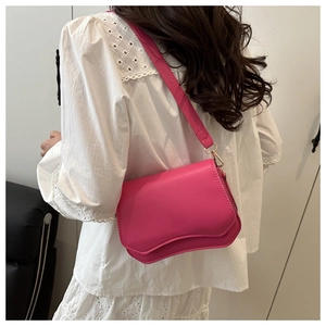 Close-up of bright pink shoulder bag with unique wavy edge and gold hardware accents
