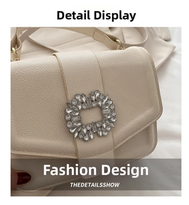 Detail of creamy white crossbody bag showing lychee pattern texture and rhinestone buckle