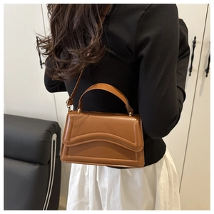 Dettaglio borsa a tracolla in pelle marrone con cuciture curve e fibbie dorate