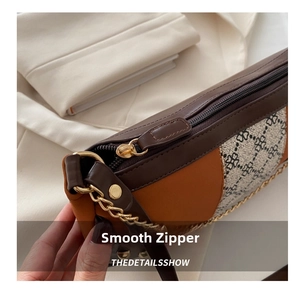 Close-up of smooth metal zipper and chain strap detail on a patchwork leather bag