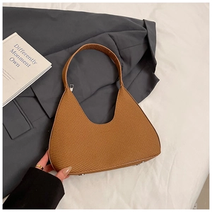 Détail du sac tissé marron avec clous de fond en métal et fermeture éclair chic