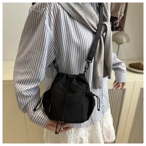 Detail of black nylon drawstring bucket bag with mesh pocket and long shoulder strap