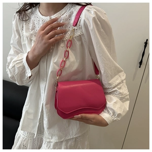 Detail of hot pink crossbody bag with wavy flap design and acrylic chain strap