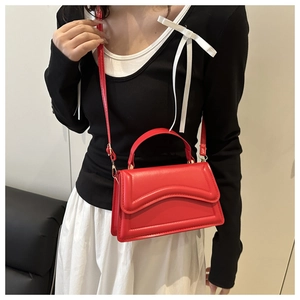 Dettaglio della borsa a tracolla rossa minimalista con patta a onde e texture in pelle