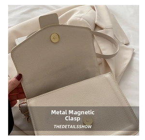 Detail of golden magnetic clasp closure on cream-colored lychee pattern leather handbag