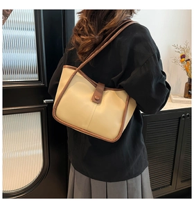 Detail of beige tote bag with brown trim shown from side-back view on shoulder