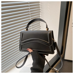 Détail du mini sac bandoulière noir avec rabat ondulé et poignée en métal doré