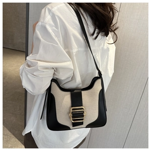 Detail of canvas shoulder bag with black leather trim and gold metal buckle strap