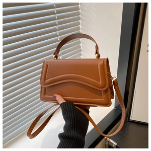 Détail d'un sac bandoulière marron avec des surpiqûres vagues élégantes et une poignée chic