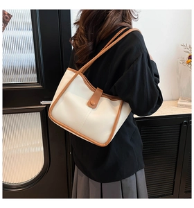 Detailed side view of a cream bucket bag with brown piping on a female model