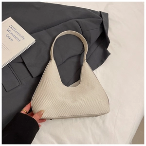 Détail du sac fourre-tout triangulaire blanc cassé avec texture fine et pieds en métal
