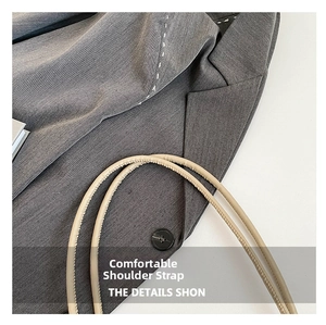 Detail of a beige leather shoulder strap with fine texture against a grey suit jacket