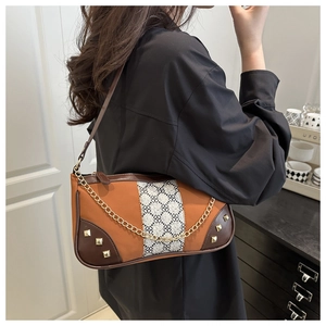 Detail of vintage underarm bag with orange trim, floral pattern, and gold hardware rivets