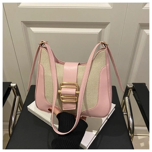 Close-up of pink leather shoulder bag with woven texture and large golden square buckle