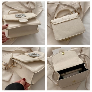 Detail view of cream leather crossbody bag with sparkling rhinestone closure and inner space