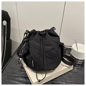 Detail of black drawstring bucket bag with mesh pocket and fashion label on nylon fabric