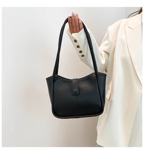 Détail d'un sac cabas noir en similicuir avec fermoir à bouton et couture sur costume blanc