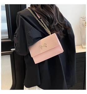 Borsa a catena rosa con fiocco dorato indossata a spalla per uno stile elegante