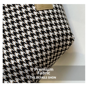 Detailed macro shot of premium houndstooth woven fabric and stitched leather tag on tote bag