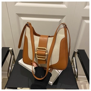 Close-up of contrast leather buckle on cream canvas shoulder bag with gold hardware