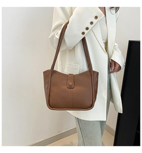 Detail of a brown matte faux leather tote bag with vertical stitching and snap closure
