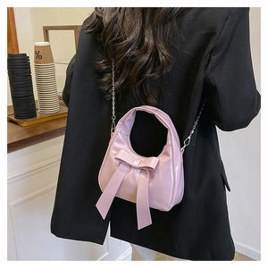Detail of pink bow hobo bag with silver chain strap worn by model in black blazer