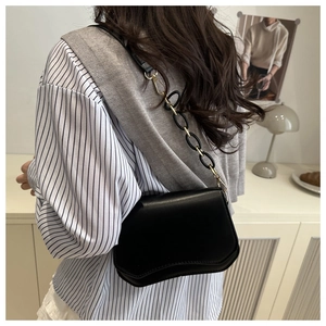 Detail of black leather bag with wavy base design and gold resin chain strap