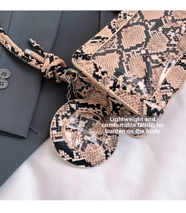 Détail d'un sac bandoulière imprimé serpent avec fenêtre transparente et pendentif