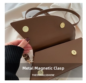 Close-up of the dual magnetic gold hardware buckles on a brown leather crossbody bag