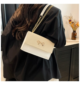 French style minimalist white chain shoulder bag with gold bow on a female model