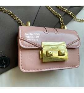 Close-up of pink mini chain bag with golden square lock on dark brown blazer