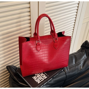Close-up of red crocodile pattern tote bag with golden metal hardware and round handles