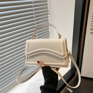 Petit sac carré moderne en cuir blanc avec poignée et finitions dorées sur fond minimaliste