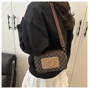 Détail d'un sac bandoulière marron à monogramme vintage avec large sangle et logo G