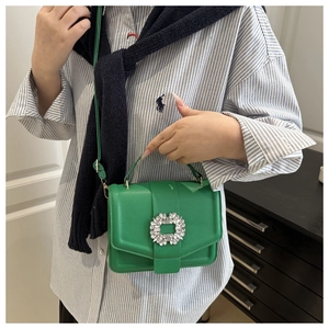 Detailed view of luxury green textured leather crossbody bag with sparkling crystal buckle