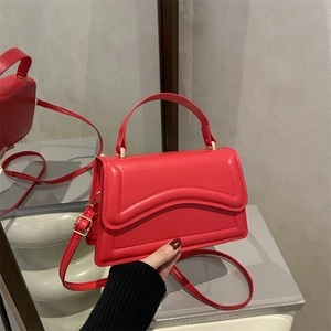 Sac à main minimaliste en cuir rouge avec surpiqûres ondulées et détails dorés sous miroirs