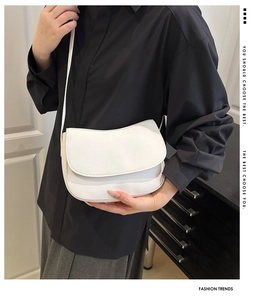 Detail of white PU leather saddle shoulder bag on model with flap closure